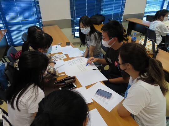 Students, tertiary student tutors, ecology experts, and GIS tutors in each group are having a discussion to decide on the group project topic.